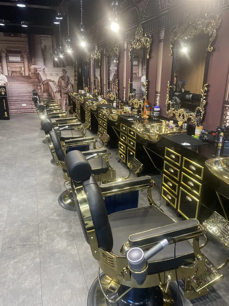 Row of black and gold barber chairs facing gold-framed mirrors inside EPHESUS TURKISH BARBER