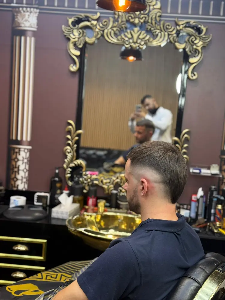 Barber checking a client's fresh fade in a baroque gold-framed mirror