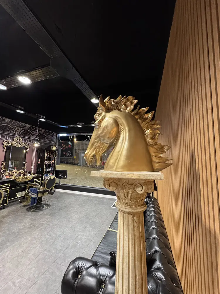 Gold horse head sculpture on a stone column beside the wood-slat wall