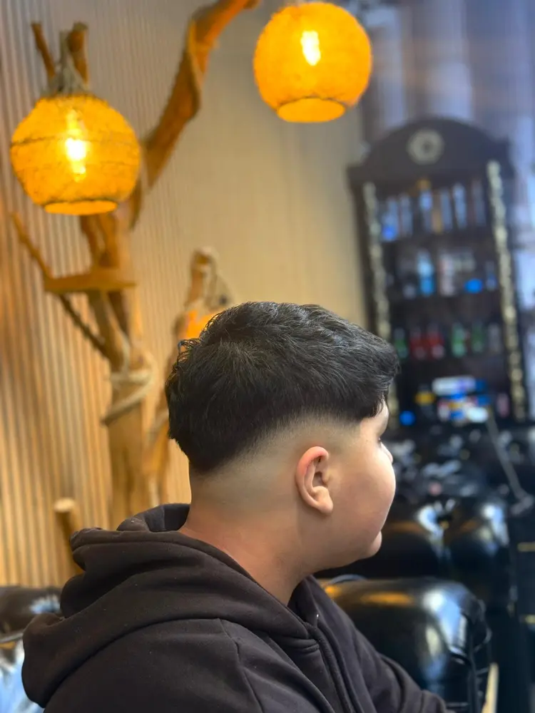 Back of a client's head showing a sharp taper fade under woven rope lamps