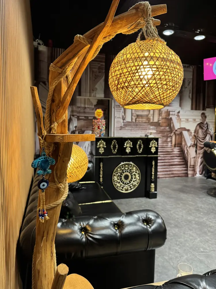 Woven rope lamps and a blue evil eye charm hanging over the black leather waiting sofa